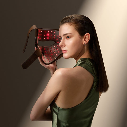 Woman using JOVS 4D laser light therapy mask for facial rejuvenation, featuring red lights for skincare.
